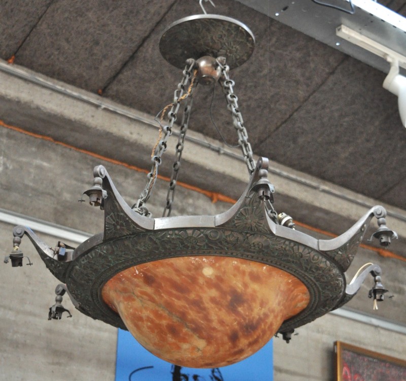 Een grote art deco luchter van brons, met acht lichtpunten, een centrale coupe van albast en zeven glazen kapjes.