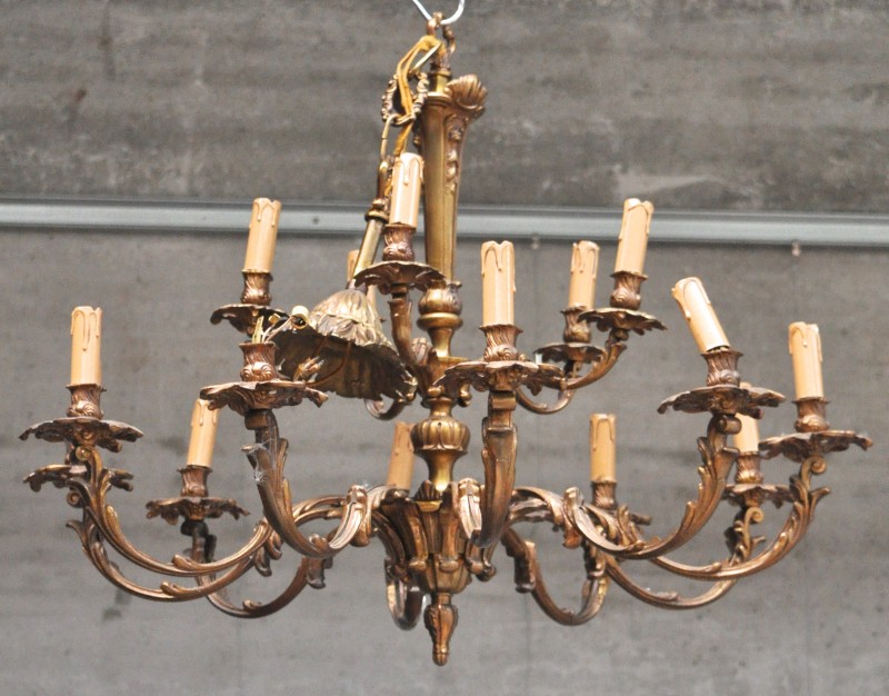 Een kroonluchter van gepatineerd brons met vijftien lichtpunten in Lodewijk XV-stijl.