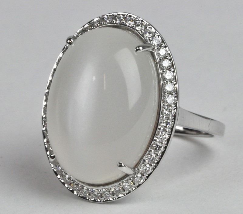 Een 18 karaats wit gouden ring bezet met diamanten met een gezamenlijk gewicht van ± 0,40 ct. en een centrale maansteen van ± 12,10 ct.