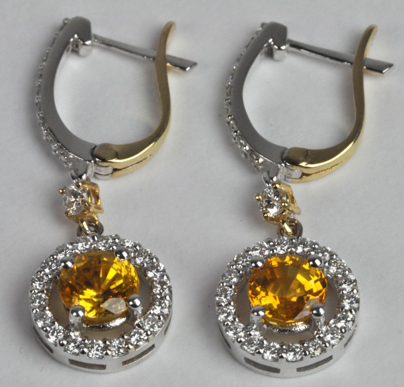 Een paar 18 karaats wit en geel gouden oorbellen bezet met diamanten met een gezamenlijk gewicht van ± 0,53 ct. en gele saffieren met een gezamenlijk gewicht van ± 1,80 ct.