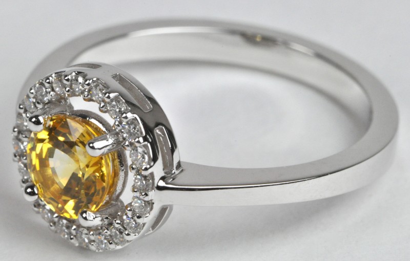 Een 18 karaats wit gouden ring bezet met diamanten met een gezamenlijk gewicht van ± 0,30 ct. en een centrale gele saffier van ± 1,08 ct.