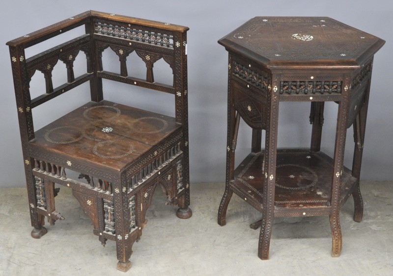 Een zeshoekig tafeltje in Arabische stijl, versierd met gebeeldhouwde geometrische patronen en enkele details ingelegd met parelmoer. Elke zijde met een uitklapbaar blaadje. We voegen er de bijhorende hoekstoel aan toe. Kleine manco’s.