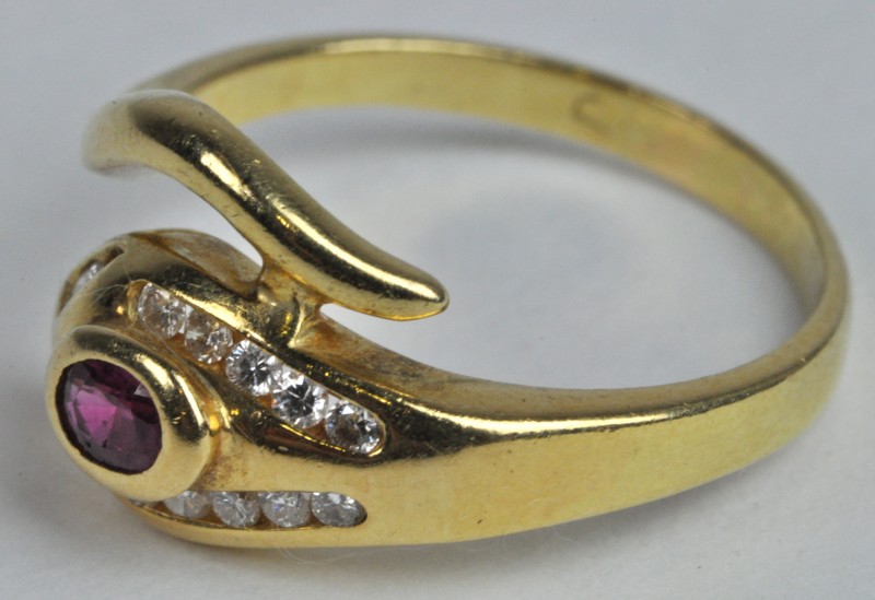 Een 18 karaats geel gouden ring bezet met diamanten met een gezamenlijk gewicht van ± 0,15 ct en een centrale robijn van ± 0,15 ct.