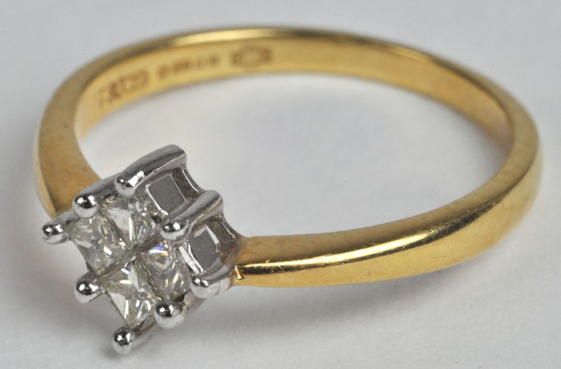 Een 18 karaats wit en geel gouden ring bezet met vier princesses met een gezamenlijk gewicht van ± 0,40 ct.