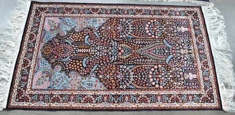 Een handgeknoopt zijden tapijt met een mihrab in het decor.
