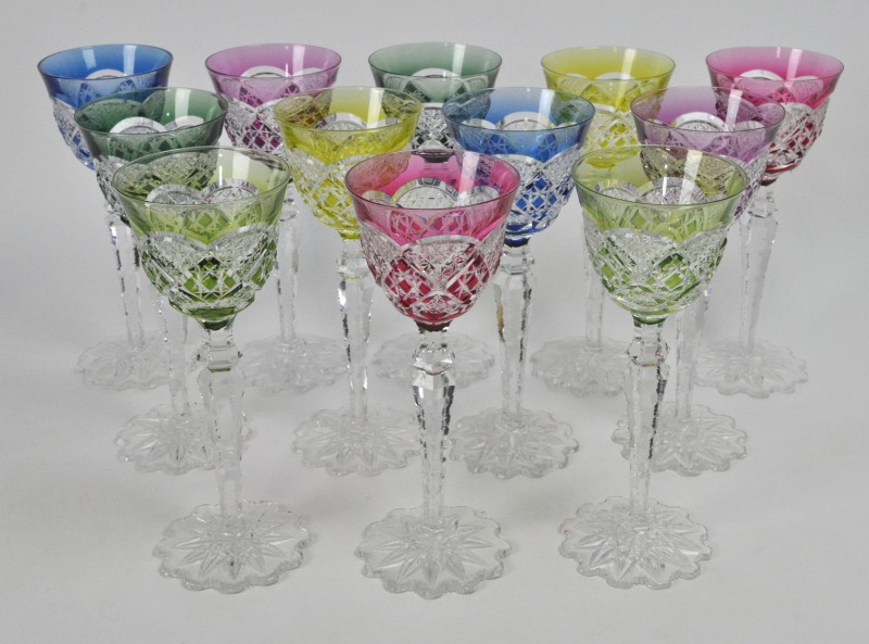 Twaalf glazen van geslepen kristal in diverse kleuren. Onderaan gemerkt.