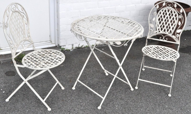 Een tuinset van witgelakt metaal, bestaande uit een tafeltje en twee stoelen.