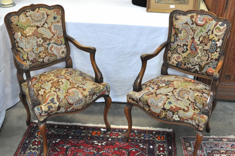 Een paar fauteuils in Lodewijk XV-stijl van gesculpteerd notenhout, bekleed met naaldwerk.