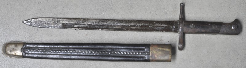 Een oude bajonet met lederen schede met koperbeslag.