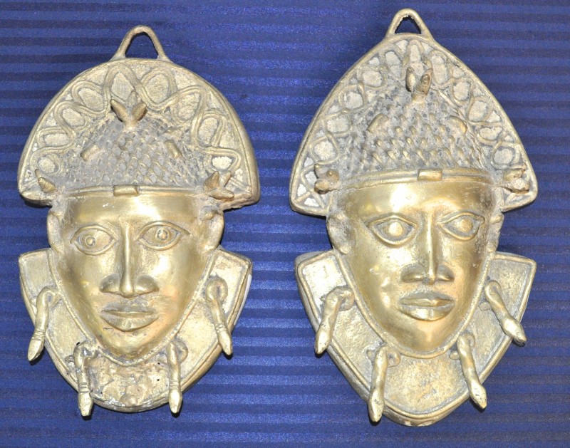 Een paar bronzen wandornamenten in de vorm van Afrikaanse hoofden.