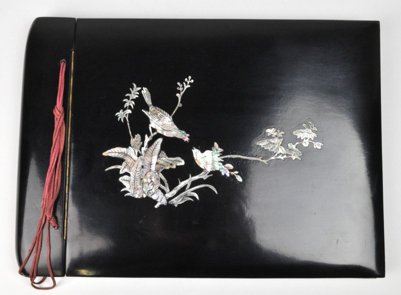 Een fotoalbum van zwart gelakt hout, met ingelegd vogelmotief van parelmoer.