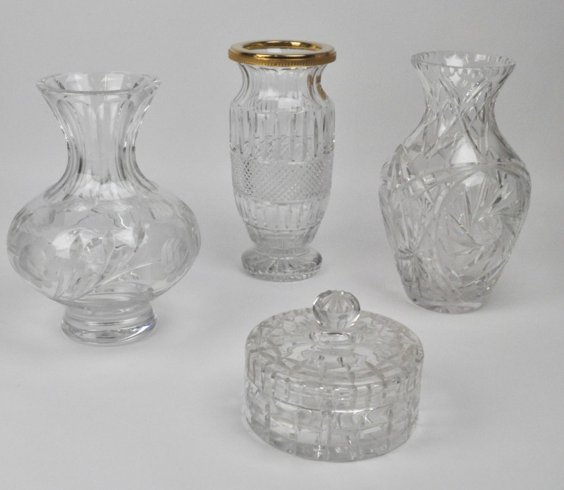 Een lot kleurloos geslepen kristal, bestaande uit drie verschillende vazen (waarvan één met vergulde montuur) en een bonbonnière.