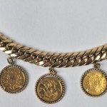 Een 18 karaats geel gouden armband, versierd met 5 oude gouden munten:- Een oud Pond uit 1880- 20 Zwitserse frank uit 1947- Een nieuw pond uit 1958- Een munt met een afbeelding van Napoleon III uit 1865- Een oud pond uit 1928.