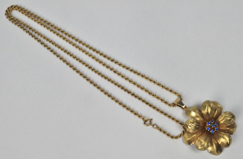 Een 18 karaats geel gouden schakelketting met een hanger in de vorm van een bloem bezet met safiertjes.