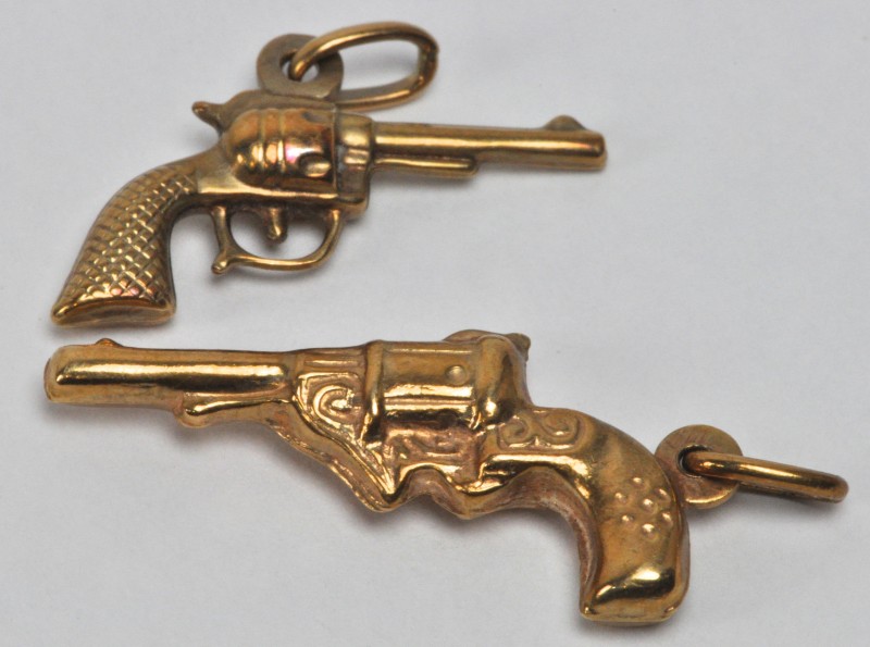 Twee hangertjes van 18 karaats geel goud in de vorm van revolvertjes.