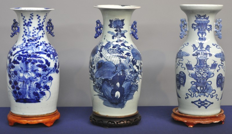 Drie vazen van Chinees blauw en wit porselein, waarvan twee met een bloemendecor. Allen op houten sokkel.