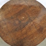 Een lage ronde tafel op centrale driepoot. Volledig versierd met intarsia van diverse houtsoorten. XIXde eeuw.