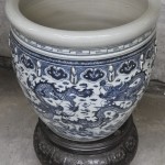 Een cachepot van blauw en wit Chinees porselein op een houten sokkel.