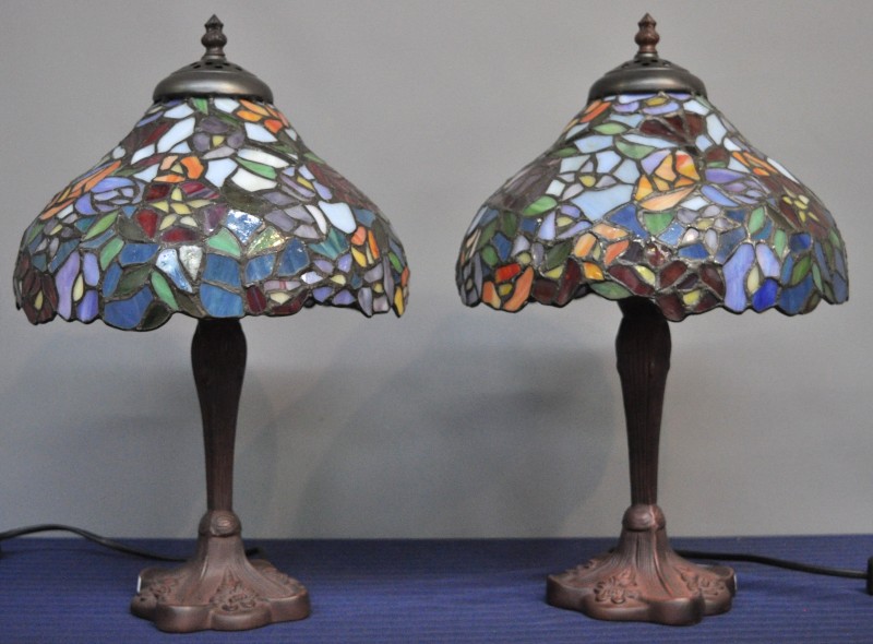 Twee lampen van donkergepatineerd metaal met glazen kappen in de geest van Tiffany.