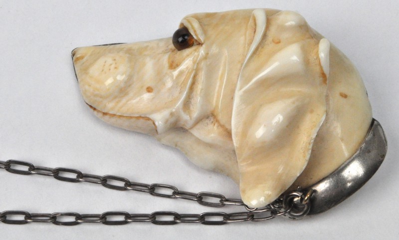 Een ivoren broche in de vorm van een jachthond.