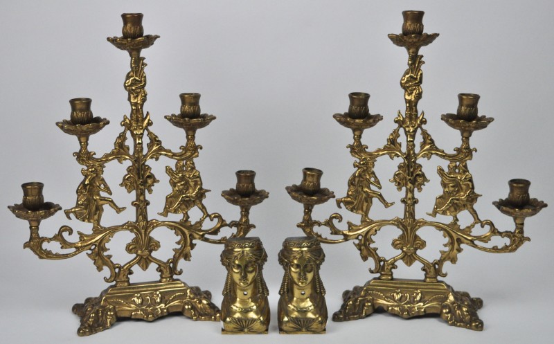 Een paar geelkoperen kandelaars met vijf lichtpunten en versierd met personages. We voegen er twee empire kastornamenten van vergulkd brons aan toe.
