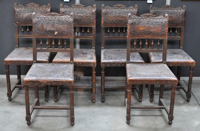 Zes stoelen van gesculpteerd notenhout en gedreven leder in renaissancestijl.