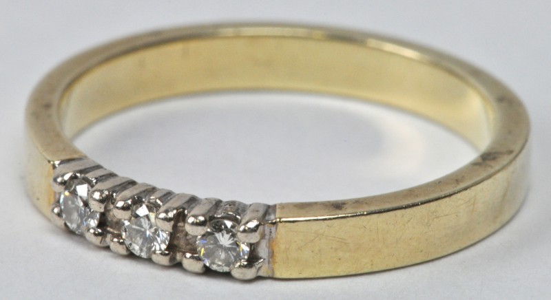 Een 14 karaats wit en geel gouden ring bezet met drie briljantjes.