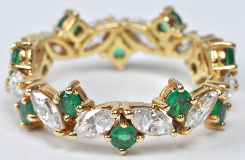 Een 18 karaats geel gouden ring bezet met briljanten met een gezamenlijk gewicht van ± 1,20 ct. en smaragden met een gezamenlijk gewicht van ± 0,60 ct.