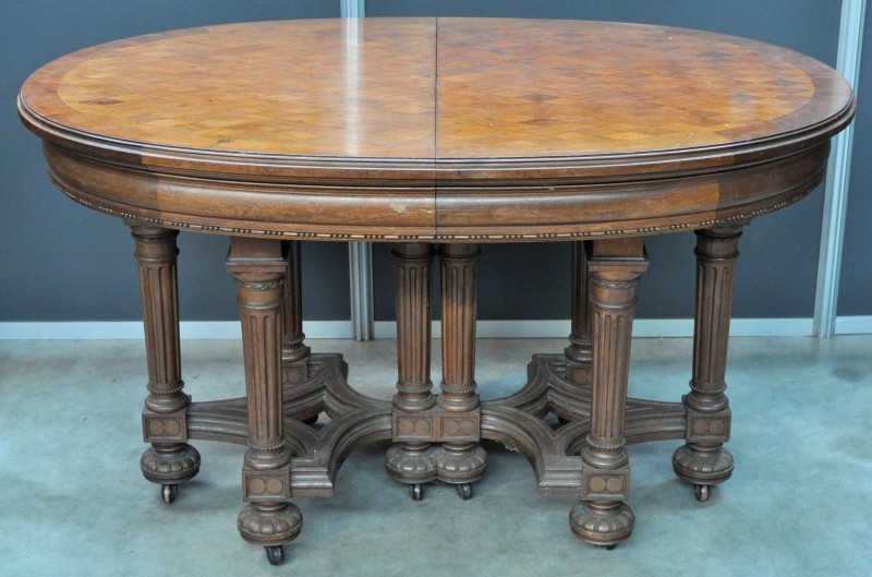 Een ovale tafel in classicistische stijl met ruitvormige parquetterie.