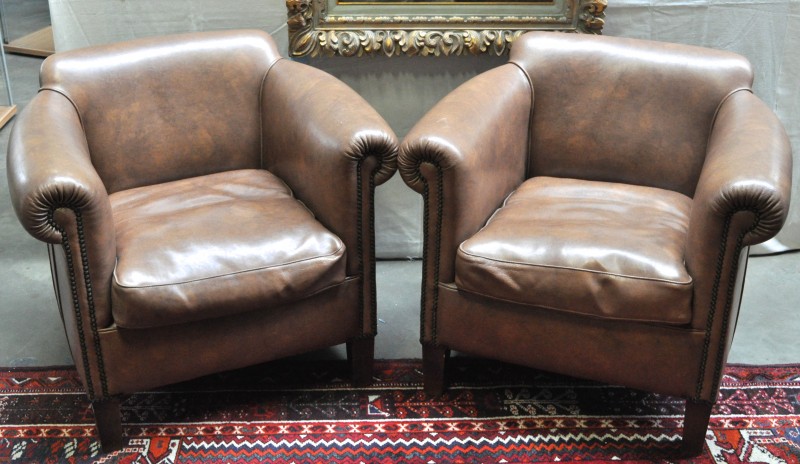 Twee fauteuils, bekleed met bruin leder. Engels werk.