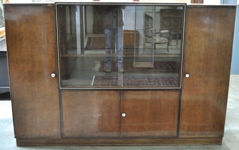 Een vitrinekast van gefineerd hout met aan weerskanten een paneeldeur.