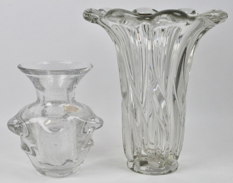 Een grote en een kleine vaas van kleurloos kristal. De eerste Oostenrijks en met getorste ribben, de tweede gemerkt Val St. Lambert.
