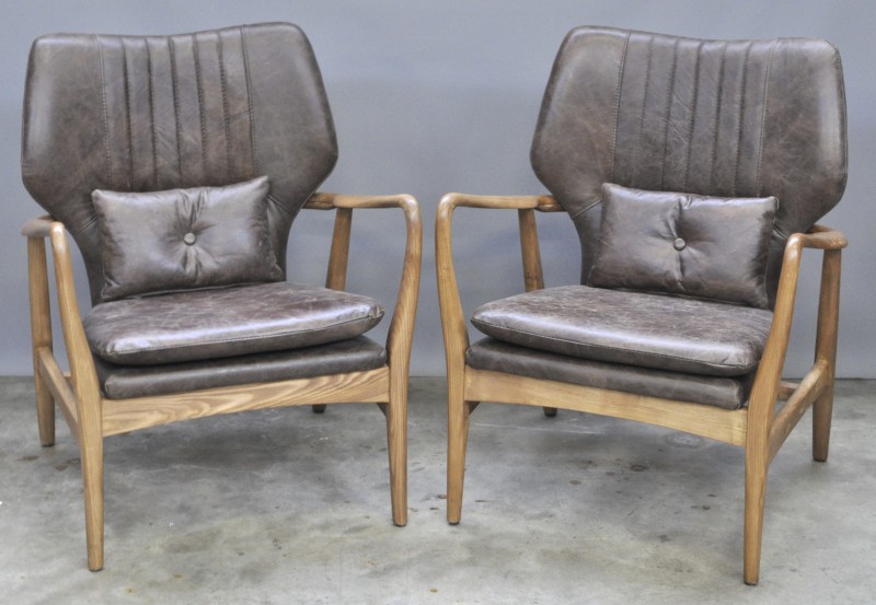 Een paar zg. “Button Chairs” van bruin leder en hout. Naar een ontwerp van Finn Juhl.