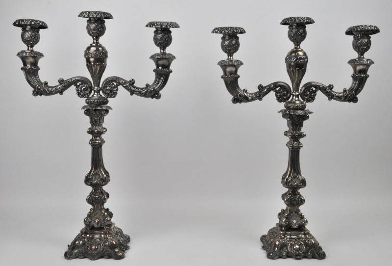 Een paar zilveren kandelaars met drie armen in barokke stijl. Belgisch importmerk van tussen 1831 en 1868. Gemerkt met ‘D’ (Delheid?).