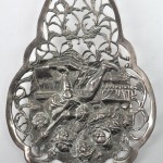 Een zilveren taartschep met een ajourwerk rond een reliëfdecor met een genretafereel. Nederlandse keur, tweede gehalte (833‰.). Tussen 1814 en 1953.