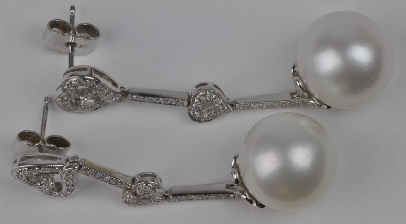 Een paar wit gouden oorbellen bezet met diamanten met een gezamenlijk gewicht van ± 0,60 ct. en twee grote parels.