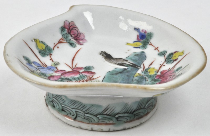 Een schaaltje op voet van Chinees porselein met een meerkleurig decor van een vogel tussen bloemen. Onderaan gemerkt.