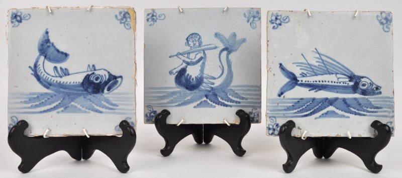 Drie aardewerken tegels met blauw en wit decor “Vissen”.