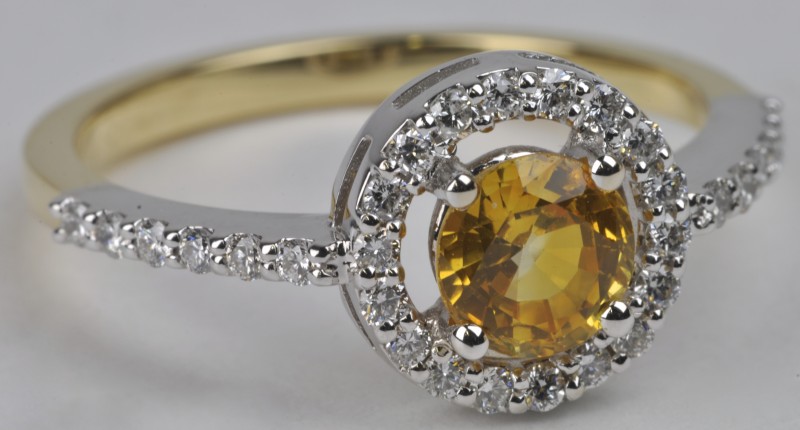 Een 18 karaats wit gouden ring bezet met diamanten met een gezamenlijk gewicht van ± 0,30 ct. en een gele saffier van ± 0,93 ct.