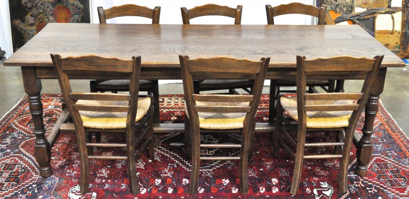 Een eikenhouten tafel met gedraaide poten in H-verbinding. We voegen er  zes bijpassende stoelen met rieten zit aan toe.