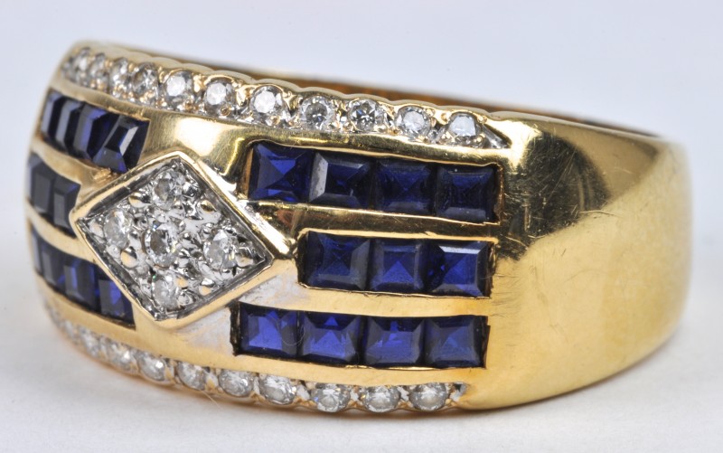 Een 18 karaats geel gouden ring bezet met diamanten met een gezamenlijk gewicht van ± 0,30 ct.  en saffier baguetten met een gezamenlijk gewicht van ± 1,10 ct.