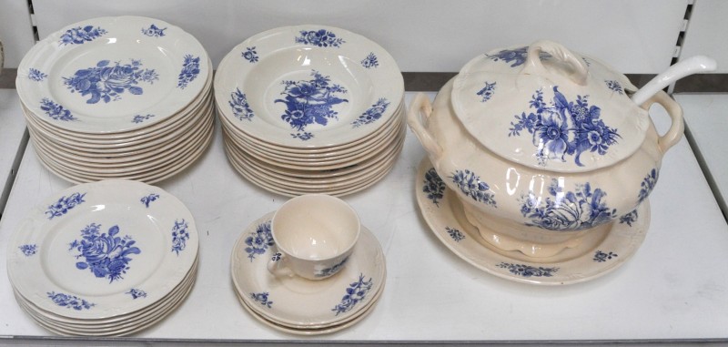 Een gedeeltelijk servies van aardewerk met een blauw ‘Rhodiadecor’, bestaande uit 15 diepe borden, 10 platte borden, 6 kleine borden, een grote soepterrine met onderschotel, een theekopje en drie onderbordjes. Onderaan gemerkt.