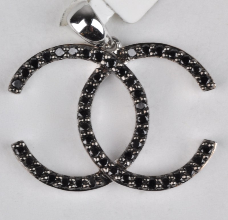 Een 18 karaats wit gouden hanger in de vorm van het embleem van Chanel bezet met zwarte briljanten met een gezamenlijk gewicht van ± 0,40 ct.