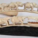 Een lot van vijf gesculpteerde ivoren tanden, waarvan vier versierd met olifantjes en een krokodil.