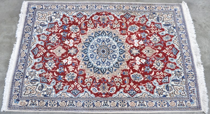 Een handgeknoopt Perzisch tapijt van wol en zijde.