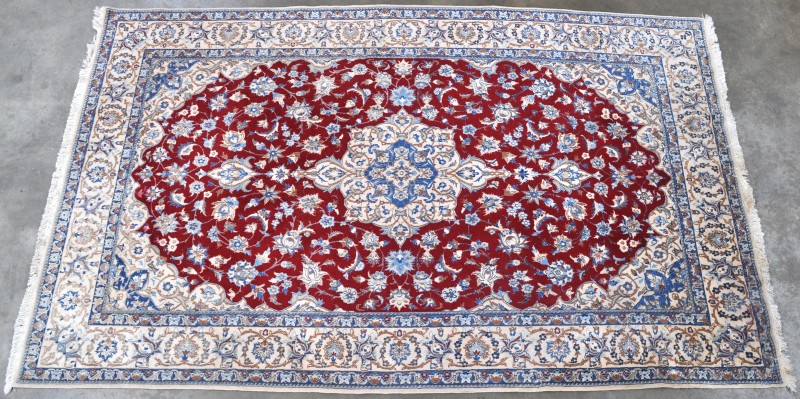 Een handgeknoopt Perzisch tapijt van wol en zijde.