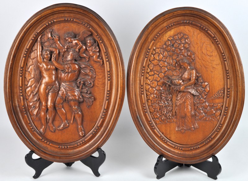 Twee ovale hoogreliëfs van gebeeldhouwd hout met afbeeldingen van mythologische taferelen. Omstreeks 1900.