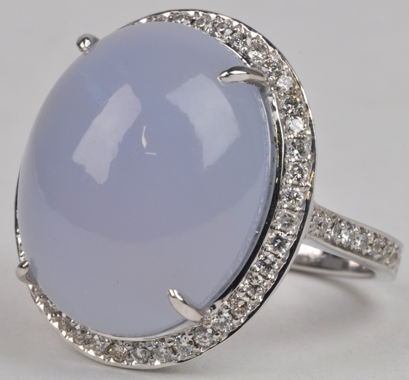 Een 18 karaats wit gouden ring bezet met diamanten met een gezamenlijk gewicht van ± 0,65 ct. en een calcedoon van ± 18,70 ct.