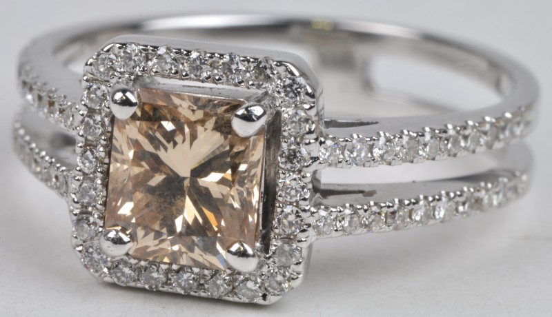 Een 18 karaats wit gouden ring bezet met diamanten met een gezamenlijk van ± 0,64 ct. en een champagne kleurige diamant van ± 0,64 ct.
