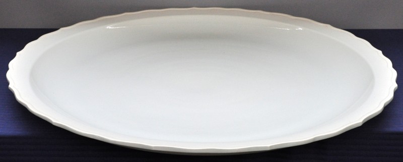 Een grote Chinese schotel van monochroom wit porselein met een accoladevormige rand.